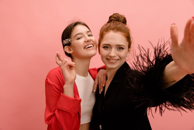 Alegres jóvenes caucásicas en camisas con sonrisas blancas como la nieve posan para la cámara sobre fondo rosa Concepto de personas de emociones de belleza