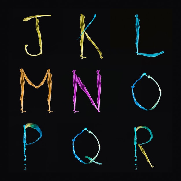 Foto gratuita alfabetos multicolores de agua de j a r sobre fondo negro