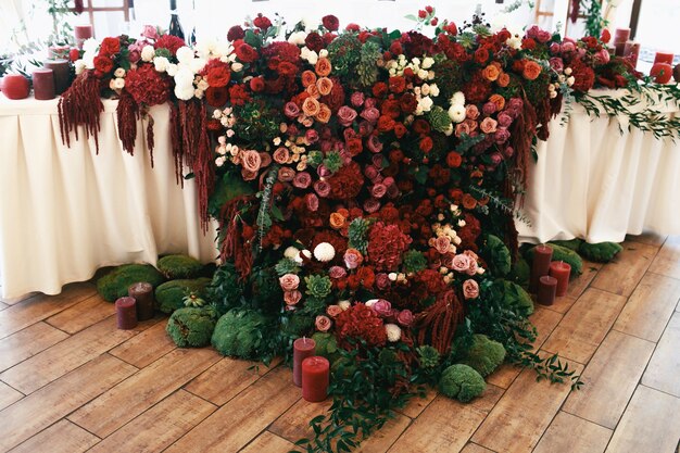 Alfombra de flores rojas y musgo cuelga de la mesa de la cena