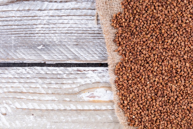 Alforfón en una tela de saco y madera blanca. vista superior. espacio para texto