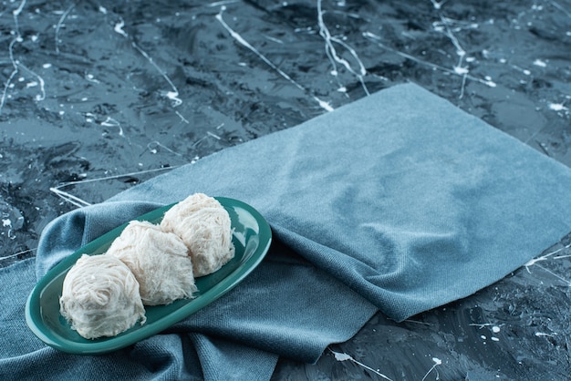 Algodón de azúcar tradicional turco en un plato sobre una toalla, sobre la mesa azul.