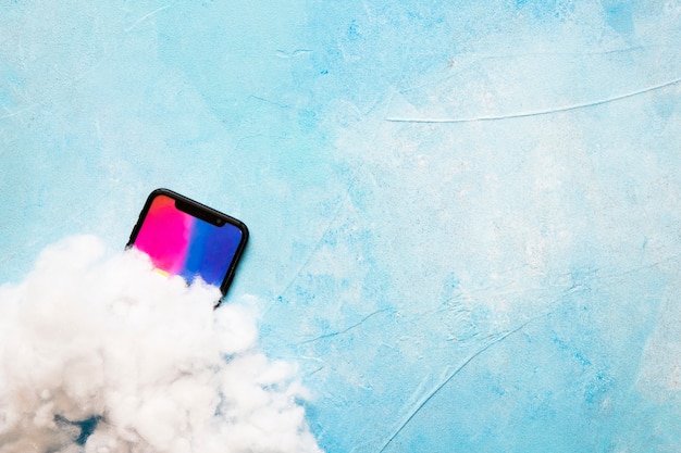 Algodón en la pantalla del teléfono móvil sobre fondo azul pintado