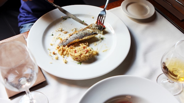 Alguien comiendo un pescado en un restaurante.