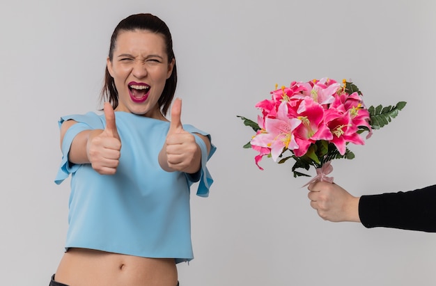 Alguien dando ramo de flores a la alegre jovencita pulgar hacia arriba