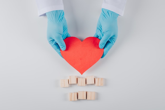 Algún corazón dentro de las manos masculinas con bloques de madera en blanco