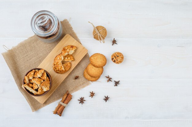 Algunas galletas con canela y clavo en un trozo de saco sobre superficie blanca