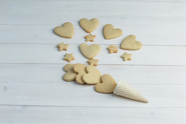 Algunas galletas con cono de galleta sobre fondo de madera, vista de ángulo alto.