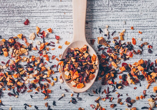 Algunas hierbas del té con la cuchara en el fondo de madera blanco, visión superior.