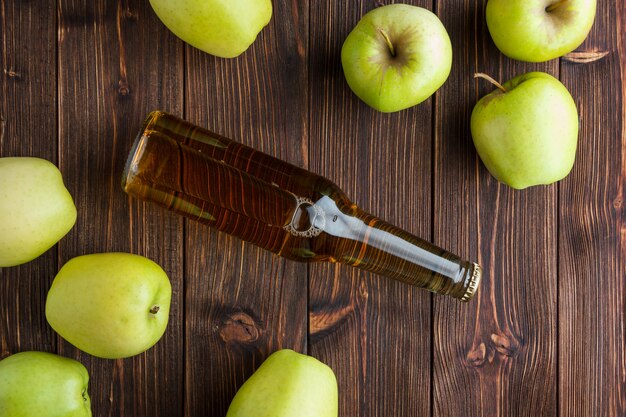 Algunas manzanas verdes con jugo de manzana sobre fondo de madera, vista superior.