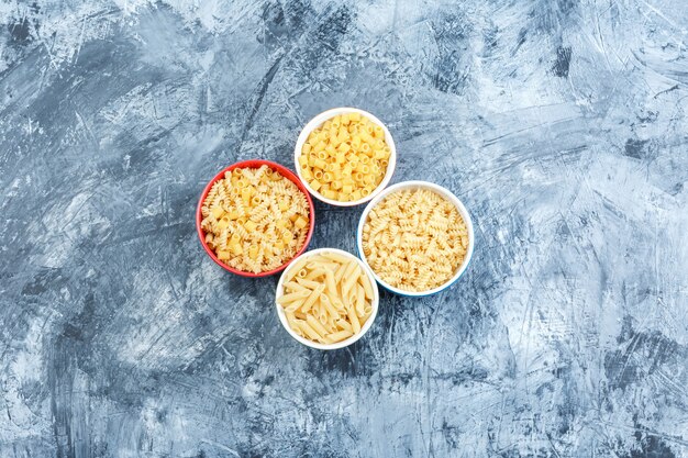 Algunas pastas variadas en tazones sobre fondo de yeso sucio, plano laical.