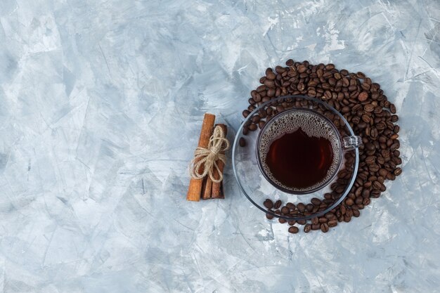 Algunos granos de café con taza de café, canela sobre fondo de mármol azul claro, plano laical. espacio libre para tu texto