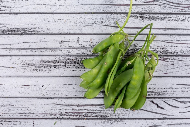 Foto gratuita algunos guisantes en mesa de madera gris