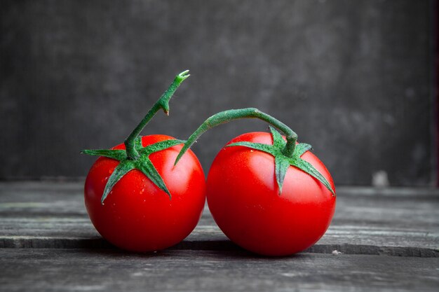 Algunos tomates en el fondo oscuro de madera y texturizado, vista lateral.