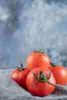 Foto gratuita algunos de tomates frescos sobre un mantel gris.