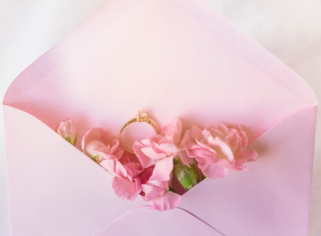 Alianza de boda en sobre con flores rosas.