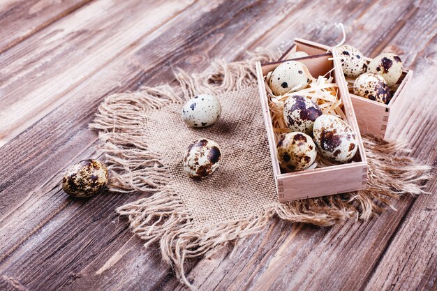 Alimentos frescos y saludables, proteínas. Huevos de codorniz en caja de madera de pie sobre la mesa rústica