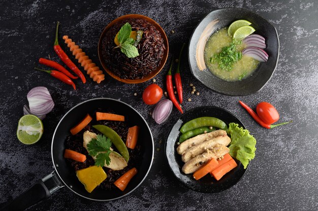 Alimentos variados y platos de verduras, carne y pescado en una mesa de piedra negra. Vista superior.