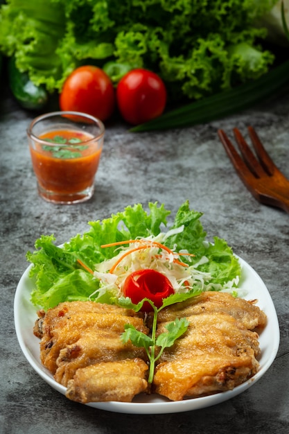 Foto gratuita alitas fritas con salsa de pescado, hierbas bellamente decoradas y servidas.