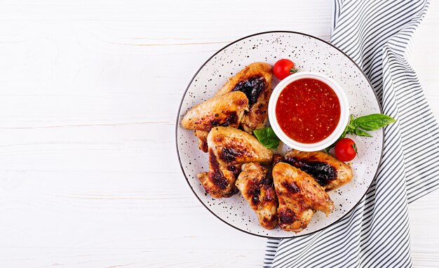 Alitas de pollo al horno al estilo asiático y salsa de tomate en un plato