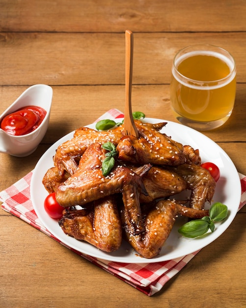 Alitas de pollo de alto ángulo en un plato con semillas de sésamo y salsa de tomate