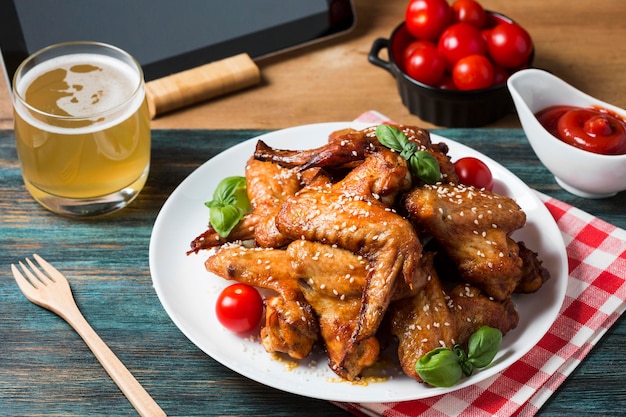 Alitas de pollo de alto ángulo en un plato con tomates cherry