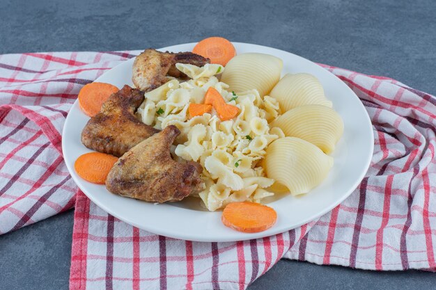 Alitas de pollo asadas y pasta en un plato blanco.