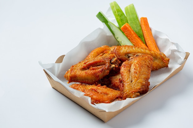 Alitas de pollo en caja de papel sobre un blanco