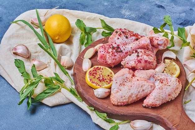 Alitas de pollo con limón sobre una tabla de madera en azul