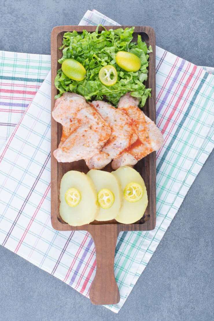Foto gratuito alitas de pollo marinadas y verduras sobre tabla de madera.