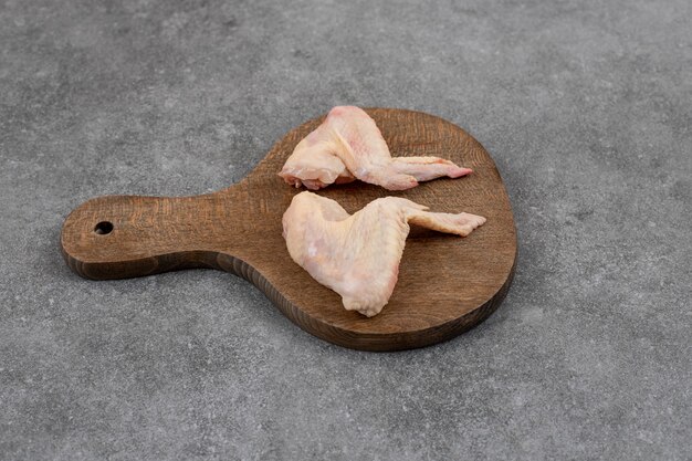 Alitas de pollo orgánicas frescas sobre tabla de cortar de madera