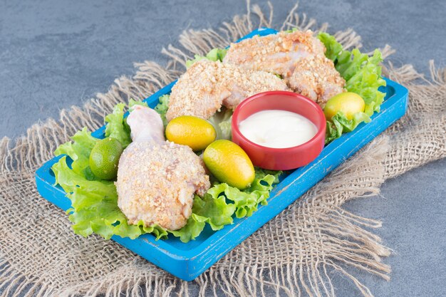 Alitas de pollo con pan rallado y verduras en placa azul.