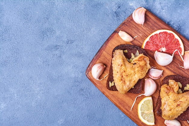 Alitas de pollo a la parrilla sobre una tabla de madera en azul