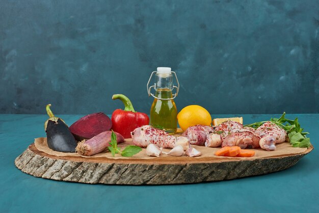 Alitas de pollo en una tabla de madera con verduras.