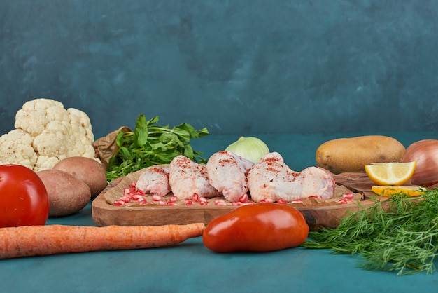 Alitas de pollo con verduras sobre una tabla de madera.