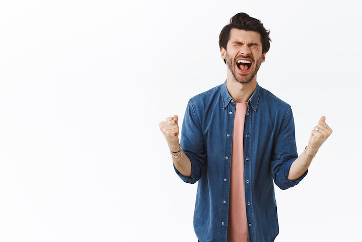 Foto gratuito aliviado, feliz, afortunado, apuesto hombre logra el sueño ganador del premio hecho realidad, cierra los ojos y grita de felicidad y alegría, aprieta las manos mientras bombea el puño triunfando y celebrando noticias increíbles