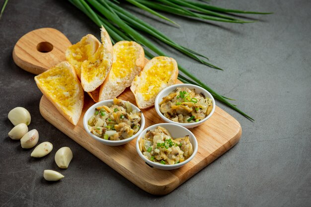 Almeja al horno con ajo y mantequilla servida con pan de ajo sobre fondo oscuro