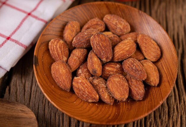 Almendras espolvoreadas con sal en un plato sobre una mesa de madera