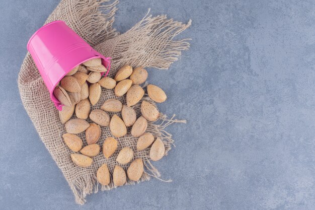 Las almendras sabrosas se derraman de un cuenco, sobre el fondo de mármol.