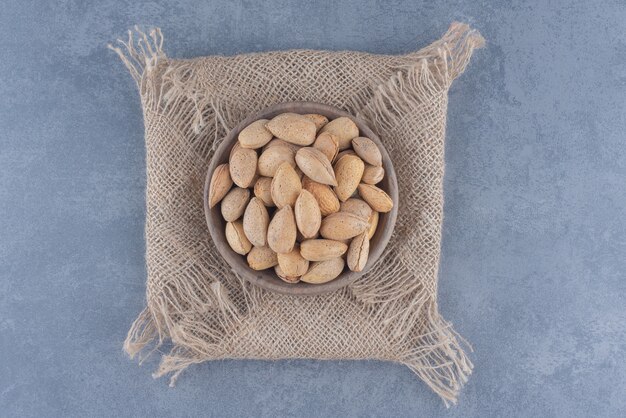 Las almendras sabrosas se derraman de un cuenco, sobre el fondo de mármol.