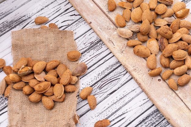 Foto gratuita almendras sobre saqueo y tabla de madera