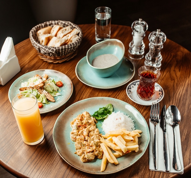 Almuerzo con sopa de champiñones Plato de pollo cremoso con arroz y papas fritas Ensalada César