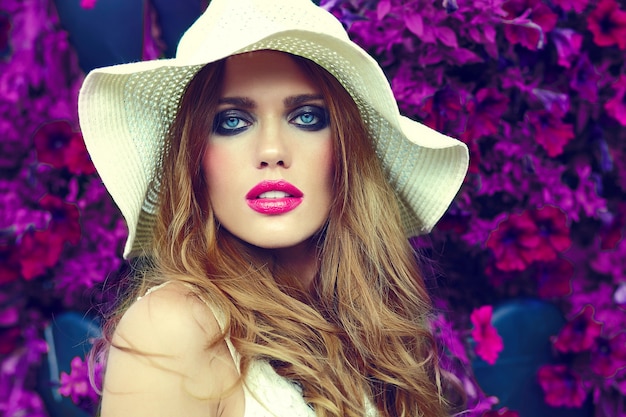 Foto gratuita alta moda look.glamor closeup retrato de hermosa sexy elegante rubia joven modelo con maquillaje brillante y labios rosados con piel limpia perfecta en sombrero cerca de flores de verano