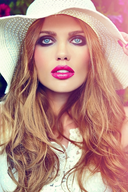 Foto gratuita alta moda look.glamor closeup retrato de hermosa sexy elegante rubia joven modelo con maquillaje brillante y labios rosados con piel limpia perfecta en sombrero cerca de flores de verano