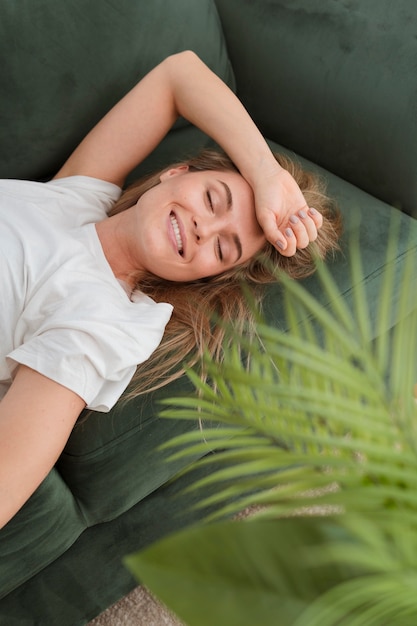 Alta vista mujer sentada en un sofá y sonriendo