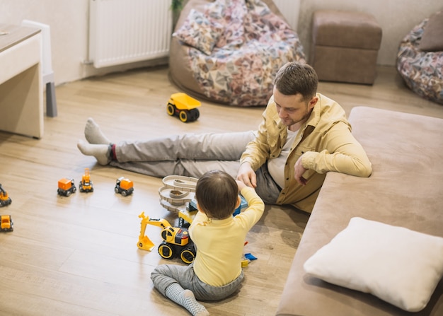 Foto gratuita alta vista padre e hijo jugando con camiones