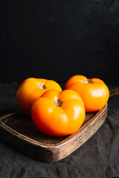 Alta vista de tomates naranjas adultos en tabla de cortar