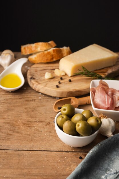 Alto ángulo de aceitunas y jamón parmesano en tabla de cortar