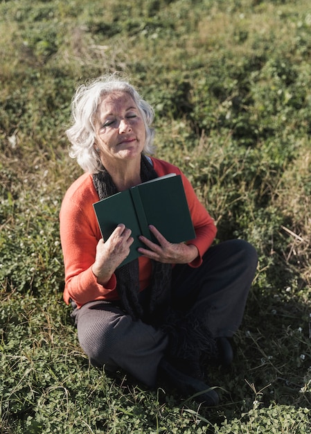 Alto ángulo anciana con libro al aire libre