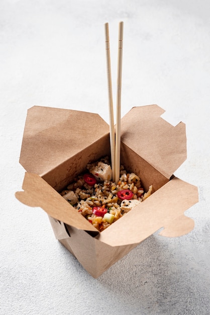 Alto ángulo de arroz y verduras para llevar con palillos