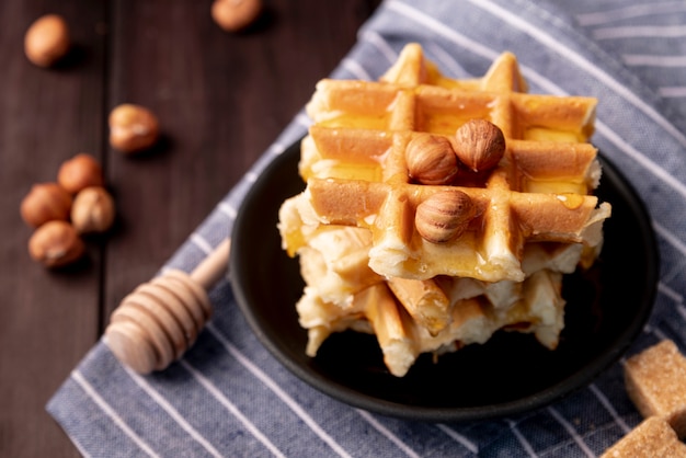 Alto ángulo de avellanas y miel sobre waffles en placa